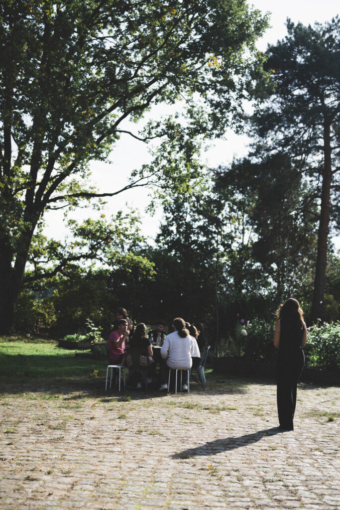 Gruppe von Menschen bei einem Outdoor-Meeting unter Bäumen bei Bahnhofszeit – Natur, Gemeinschaft und produktive Gespräche.